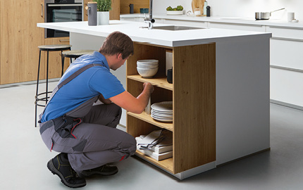 Küchenmontage: Fachkraft installiert Regal in moderner Küche
